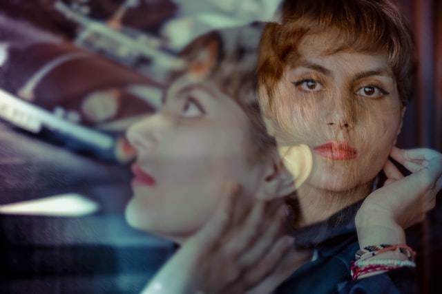 A double exposure of a woman with short hair in a turquoise shirt.