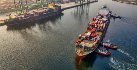 Boats unloading shipping containers in a harbor.