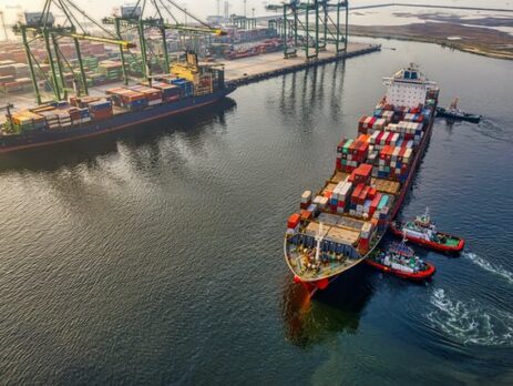 Boats unloading shipping containers in a harbor.