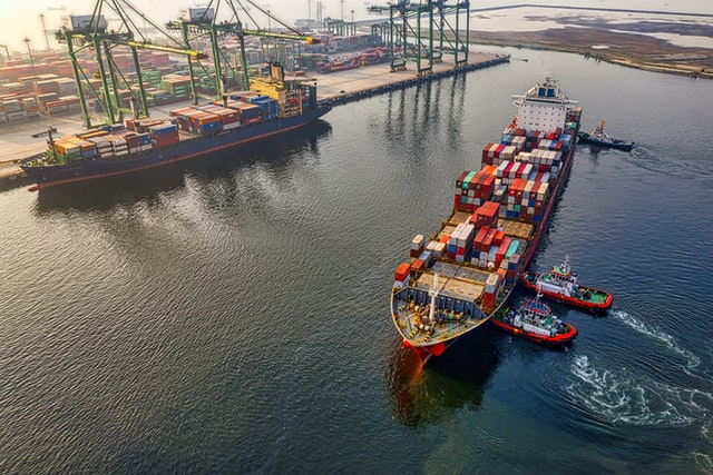 Boats unloading shipping containers in a harbor.