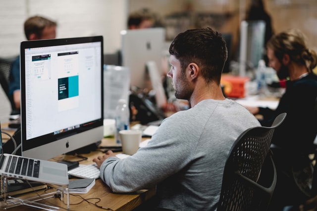 A man looks at a computer screen as he navigates with the mouse.