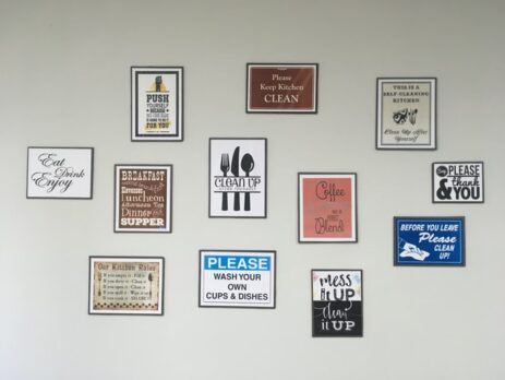 Various framed signs hanging on a white wall.