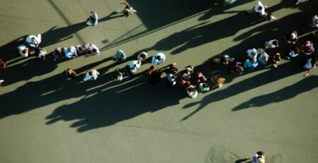 A large group of people stands in line outside.