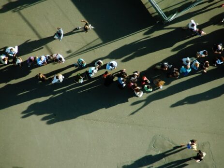 A large group of people stands in line outside.