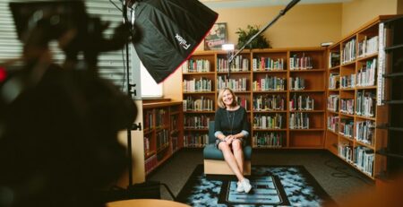 A crew filming an interview with a woman in a library.