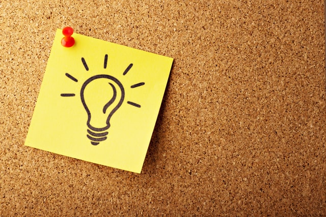 A lightbulb is drawn on a sticky note on a corkboard.