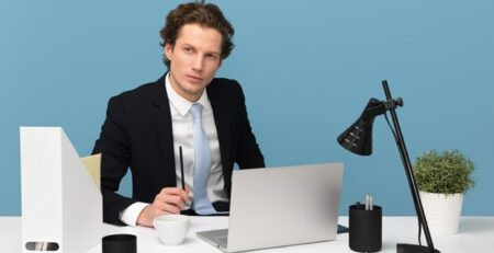 A man sits behind a desk thinking.