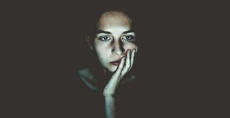 A woman illuminated by a computer screen.