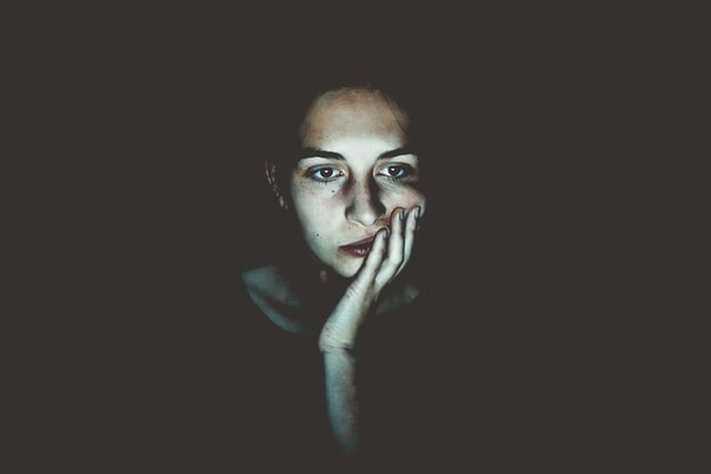 A woman illuminated by a computer screen.