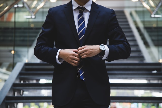With his face cut from the photo a man buttons up his jacket.