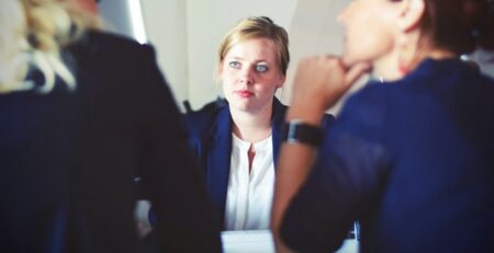 A woman sits across from her interviewers.