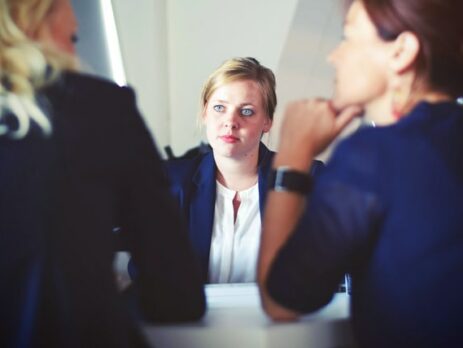 A woman sits across from her interviewers.