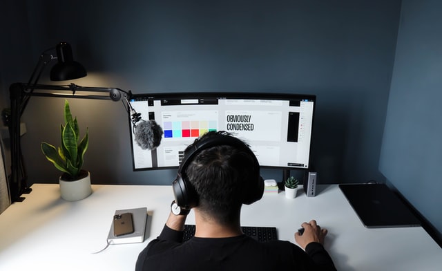A graphic designer works on a project using a dual screen setup.