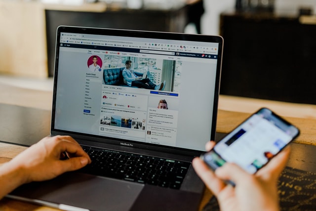 A social media manager is working on their phone and computer.