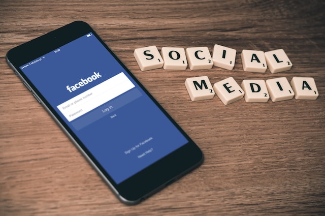 An iPhone with Facebook on the screen next to tiles that spell social media.