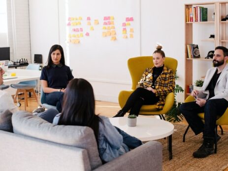 A business team sits in a circle discussing strategy. 