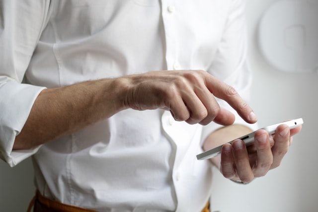 A man types in a number on a cell phone.