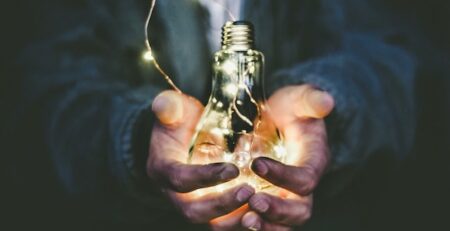 A man holds a lightbulb with a string of lights inside. 