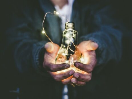 A man holds a lightbulb with a string of lights inside. 