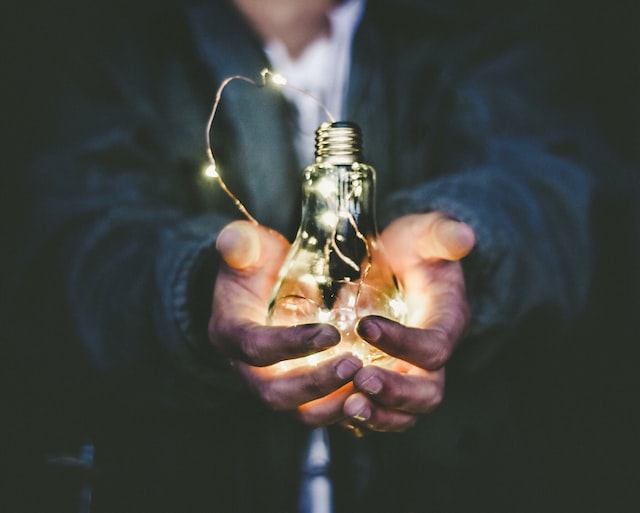 A man holds a lightbulb with a string of lights inside. 