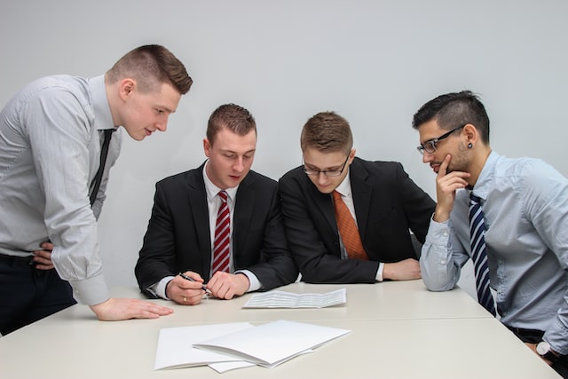 A group of four men discusses the negotiation schedule in front of them.