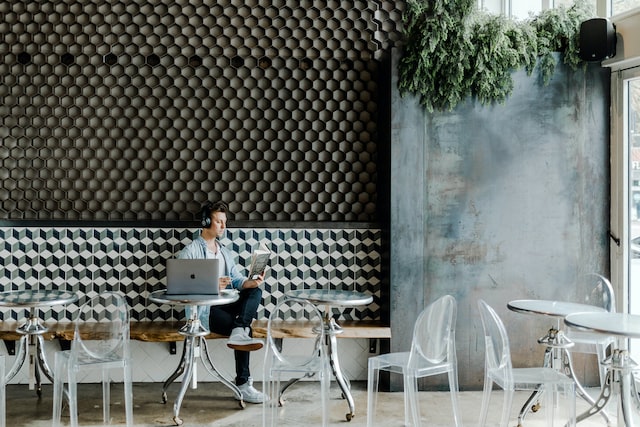 People man reads a book in a coffee shop with headphones on.