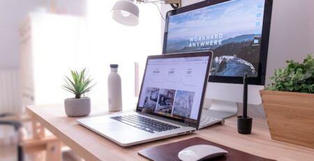 A laptop is in front of a desktop computer and both display a cool website. 