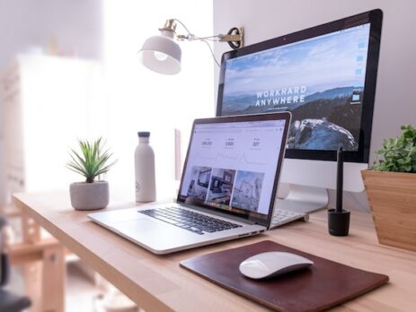 A laptop is in front of a desktop computer and both display a cool website. 