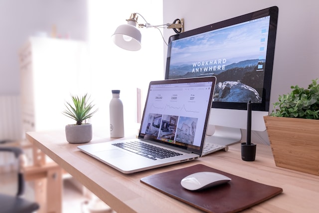 A laptop is in front of a desktop computer and both display a cool website. 