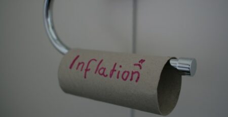 An empty toilet paper tube with inflation written on it and a sad smiley. 