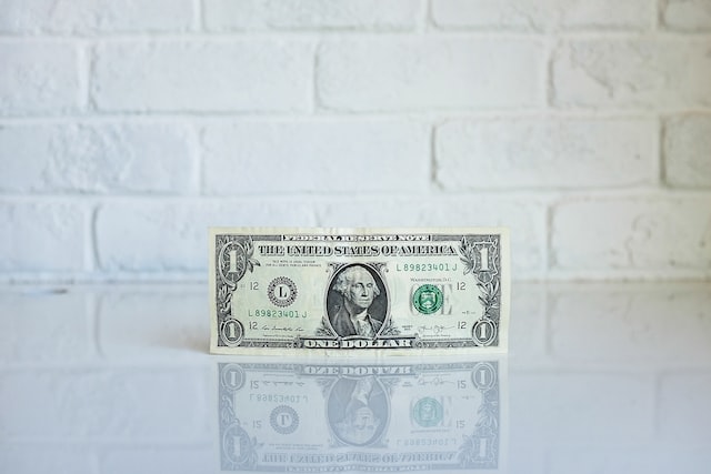 A dollar bill on a white countertop. 