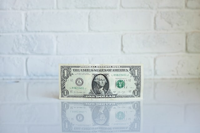 A dollar bill on a white countertop.