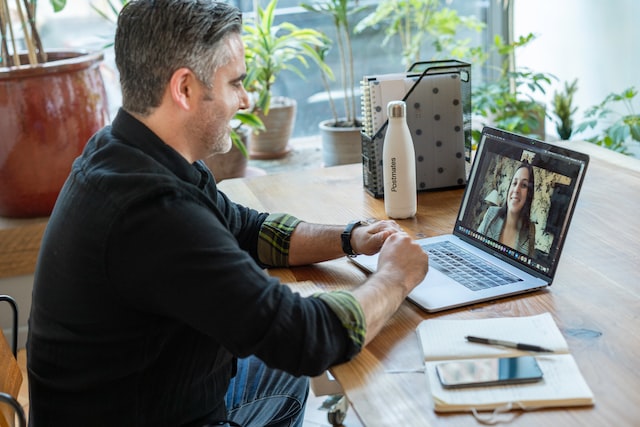 A man is being interviewed by a woman via a video interview. 