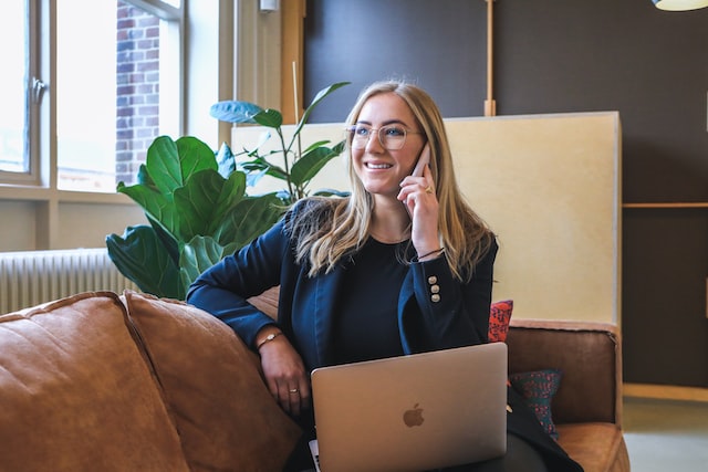 A woman sits on a couch and completes a video and phone interview.