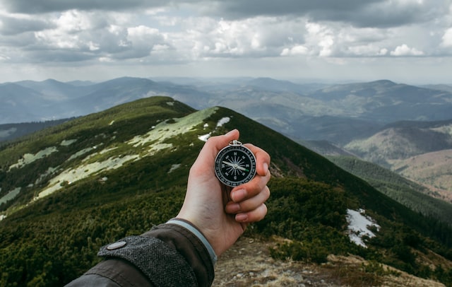 A hand holds a compass against a tropical backdrop.