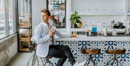 A man sits at the countertop in a modern bar. 