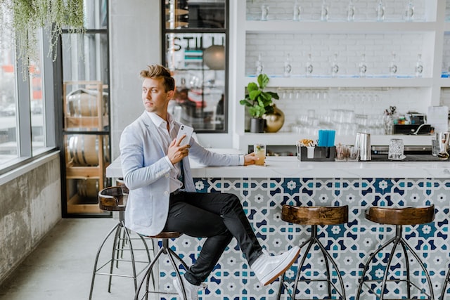 A man sits at the countertop in a modern bar. 