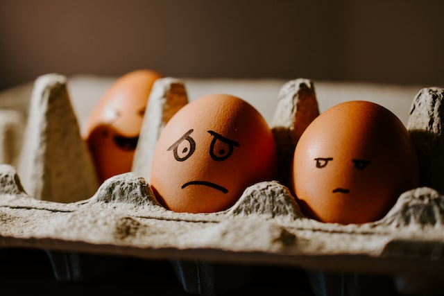 Two eggs are in a carton and have sad faces on them.