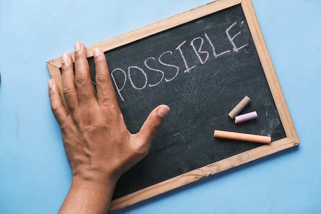 A hand on a chalkboard next to the word possible.