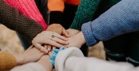 A group of people all place their hand in the center of a circle. 