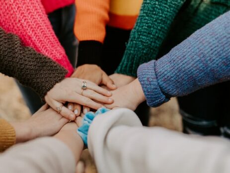 A group of people all place their hand in the center of a circle. 