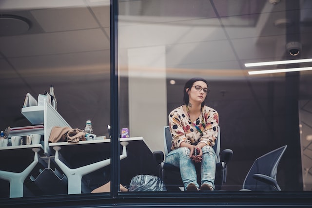 A woman sits in an office and stares out the window.
