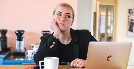 A woman sits bored in front of her laptop. 