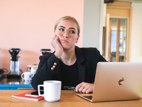 A woman sits bored in front of her laptop. 