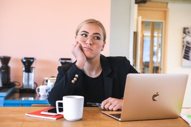A woman sits bored in front of her laptop. 
