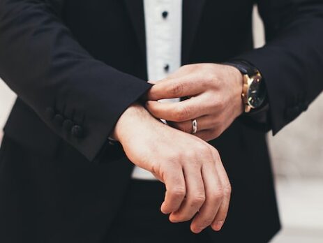 A man pulls down his suit sleeves. 