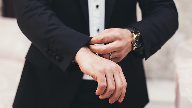 A man pulls down his suit sleeves. 