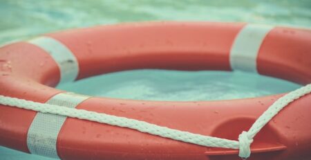 An orange life preserver floats in a pool. 