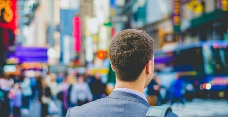 A man in a suit walks in a busy city. 