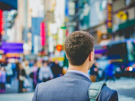 A man in a suit walks in a busy city. 